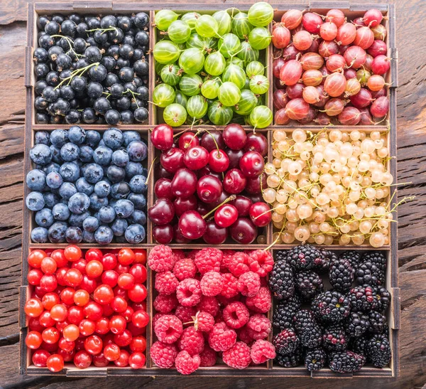 Colorful berries in wooden crate on the table. Top view. — Stock Photo, Image