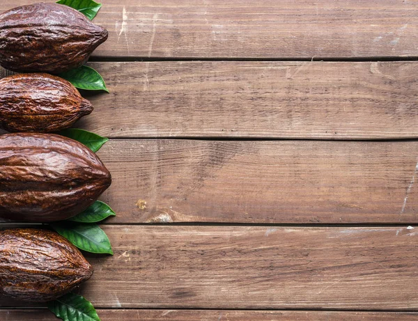 Какао стручок и листья какао расположены как часть рамы на деревянной — стоковое фото