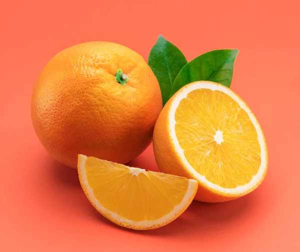 Orange fruit with orange slices and leaves isolated on orange ba