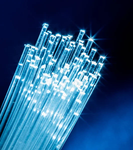 Bundle of optical fibers with lights in the ends. Blue backgroun — Stock Photo, Image