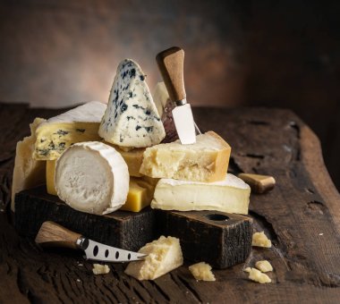 Assortment of different cheese types on wooden background. Chees clipart