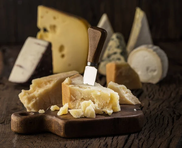 Pedaço de queijo parmesão na tábua de madeira. Sortimento de dif — Fotografia de Stock