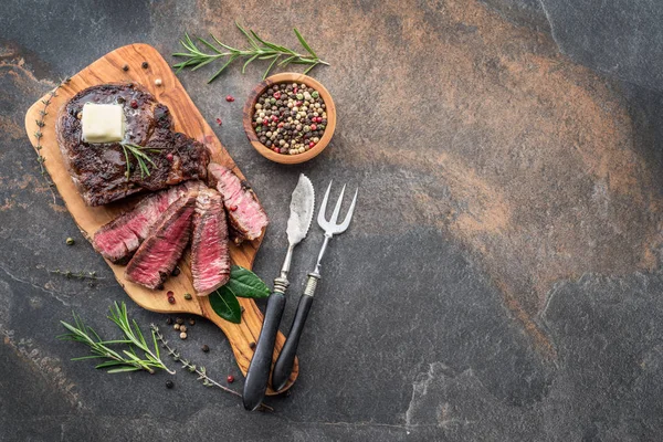 Bife Ribeye médio raro com ervas e um pedaço de manteiga no — Fotografia de Stock