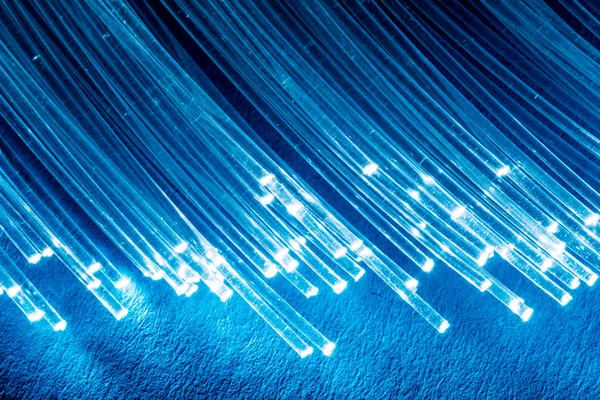 Bundle of optical fibers with lights in the ends. Blue backgroun — Stock Photo, Image