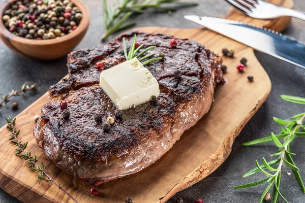 Steak de Ribeye moyen et rare avec des herbes et un morceau de beurre sur le — Photo