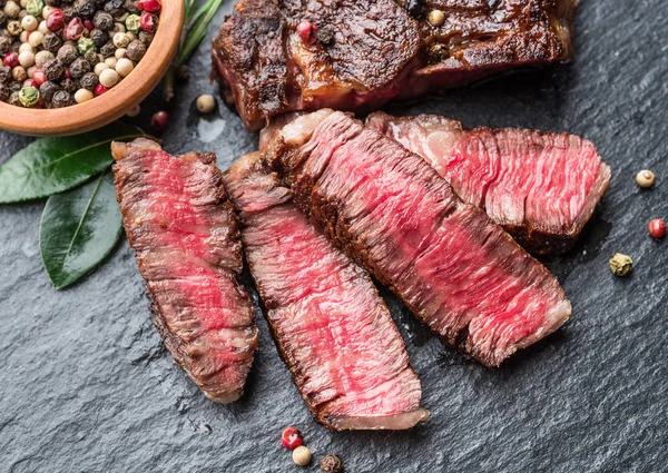 Středně vzácný steak z Ribeye s bylinkami na grafitové desce. — Stock fotografie