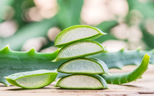 Färsk aloe lämnar och aloe gel i den kosmetiska burken på trä-fliken — Stockfoto