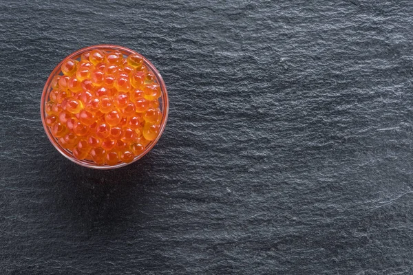 Red caviar in the bowl on gray graphite background. Top view. — Stock Photo, Image