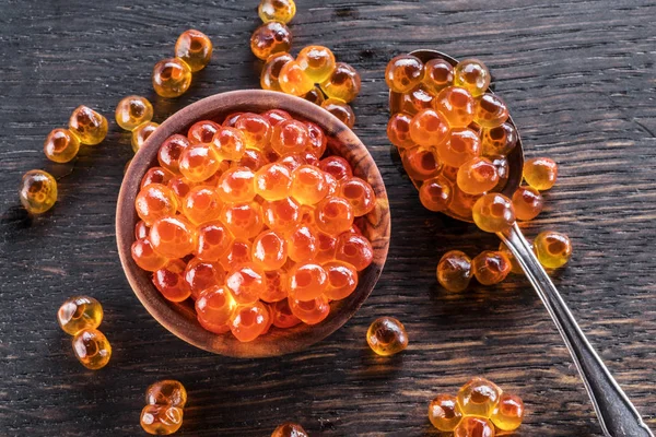 Red caviar in the bowl  and spoon on wooden background. — Stock Photo, Image