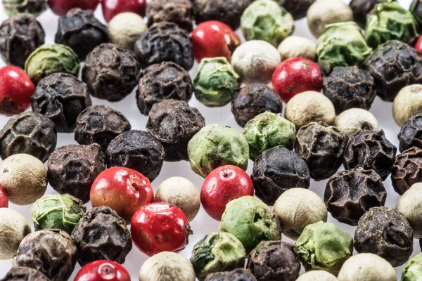 Grani di pepe neri, bianchi, verdi e rossi isolati su dorso bianco — Foto Stock