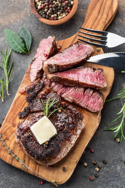 Bife Ribeye médio raro com ervas e um pedaço de manteiga no — Fotografia de Stock