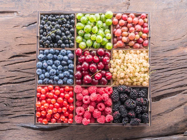 Bunte Beeren in Holzkiste auf dem Tisch. Ansicht von oben. — Stockfoto