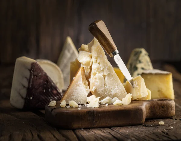 Pedaço de queijo parmesão na tábua de madeira. Sortimento de dif — Fotografia de Stock