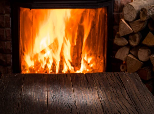 Κενό ξύλινο τραπέζι και τζάκι με θερμή πυρκαγιά στο αμουδερές — Φωτογραφία Αρχείου