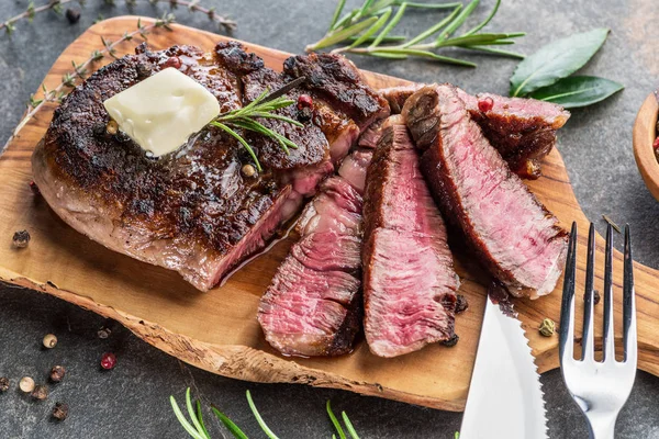 Středně vzácný steak z Ribeye s bylinkami a kusem másla na — Stock fotografie