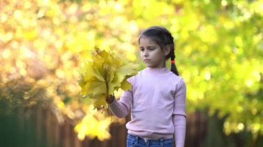 Açık havada Kız oynuyor ve sonbahar yaprakları ile sevinir. 4k video.