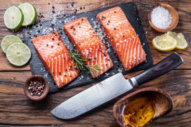Otlar, baharatlar ile siyah kesme tahtası üzerinde taze somon fileto
