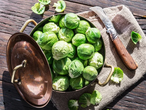 Brysselkål i koppar pannan på det gamla träbordet. — Stockfoto