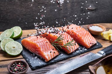 Otlar, baharatlar ile siyah kesme tahtası üzerinde taze somon fileto