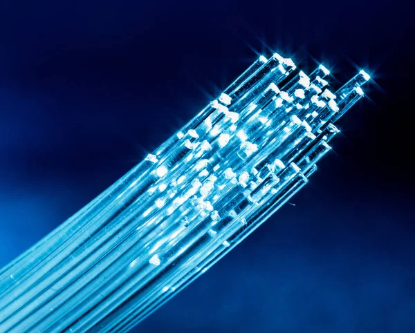 Bundle of optical fibers with lights in the ends. Blue backgroun — Stock Photo, Image