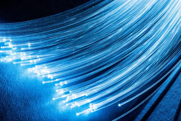 З'єднання оптичних волокон з вогнями на кінцях. Блакитний фон — стокове фото