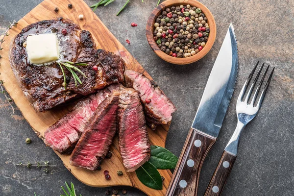 Otlar ve tereyağı bir parça ile Orta nadir Ribeye biftek — Stok fotoğraf