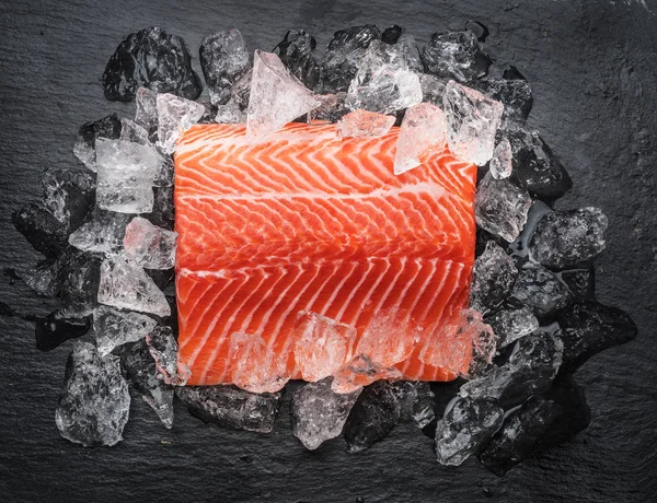 Filetto di salmone fresco sopra ghiaccio sul tagliere nero . — Foto Stock
