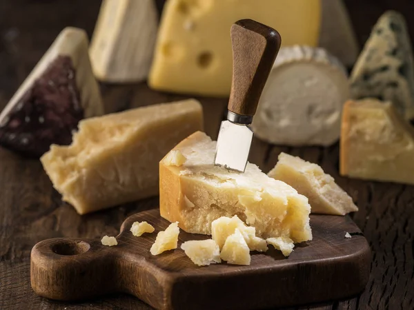 Pedazo de queso parmesano en la tabla de madera. Surtido de dif — Foto de Stock