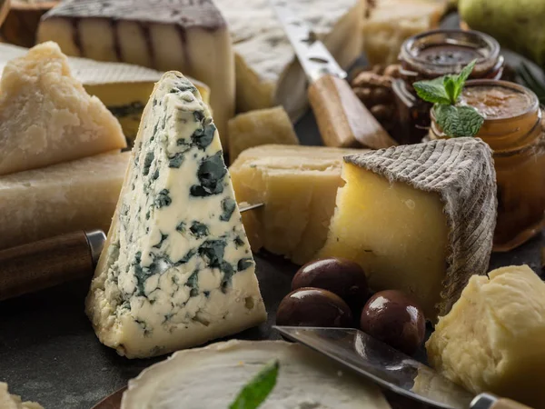 Surtido de diferentes quesos con aceitunas y mermeladas. Respaldo alimenticio —  Fotos de Stock