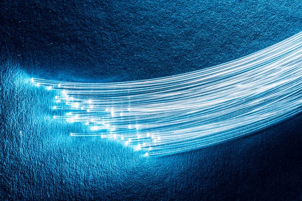 Bundle of optical fibers with lights in the ends. Blue backgroun — Stock Photo, Image