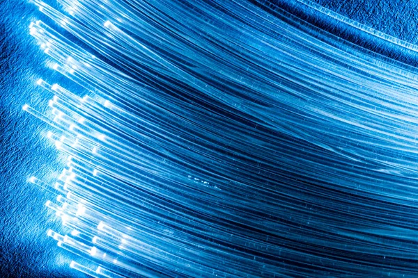 Bundel van optische vezels met verlichting in de uiteinden. Blauwe backgroun — Stockfoto