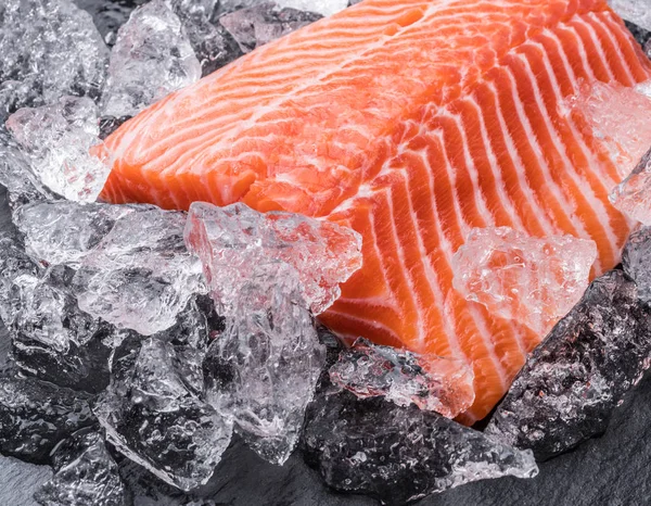 Filet de saumon frais sur glace sur planche à découper noire . — Photo