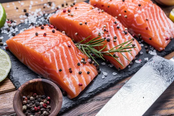 Verse zalmfilets op zwarte snijplank met kruiden en specerijen — Stockfoto