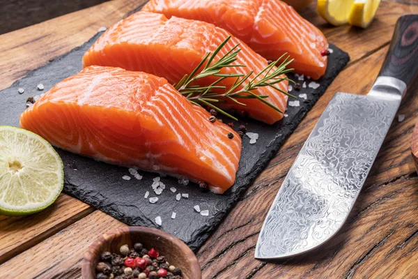 Fresh salmon fillets on black cutting board with herbs and spice — Stock Photo, Image