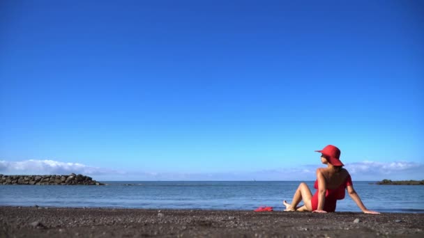 Una Donna Costume Bagno Rosso Cappello Siede Una Spiaggia Sabbia — Video Stock