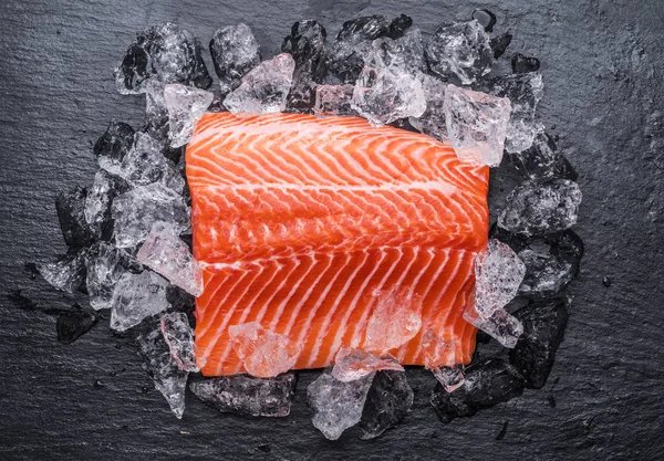 Filetto di salmone fresco sopra ghiaccio sul tagliere nero . — Foto Stock