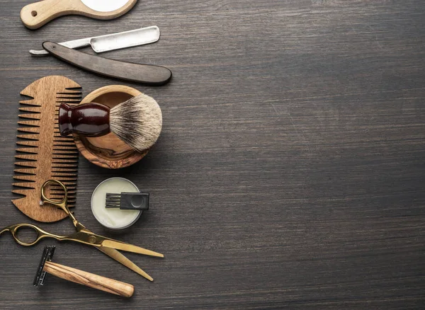 Ahşap arka planda klasik kuaför ve kuaför aletleri. Koyu renk ahşap masada duran berber dükkanının enstrümanlarının üst görüntüsü.