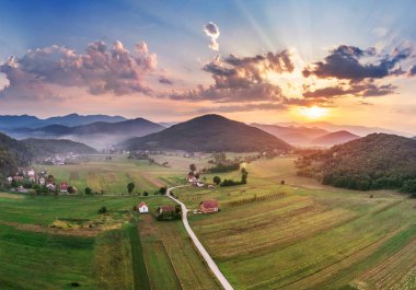 Hırvatistan 'da dağlarda güzel bir gün batımı. Kuşbakışı muhteşem gökyüzü manzarası ve vadi üzerinde bulutlar uçuşan kırmızı güneş ışıkları..
