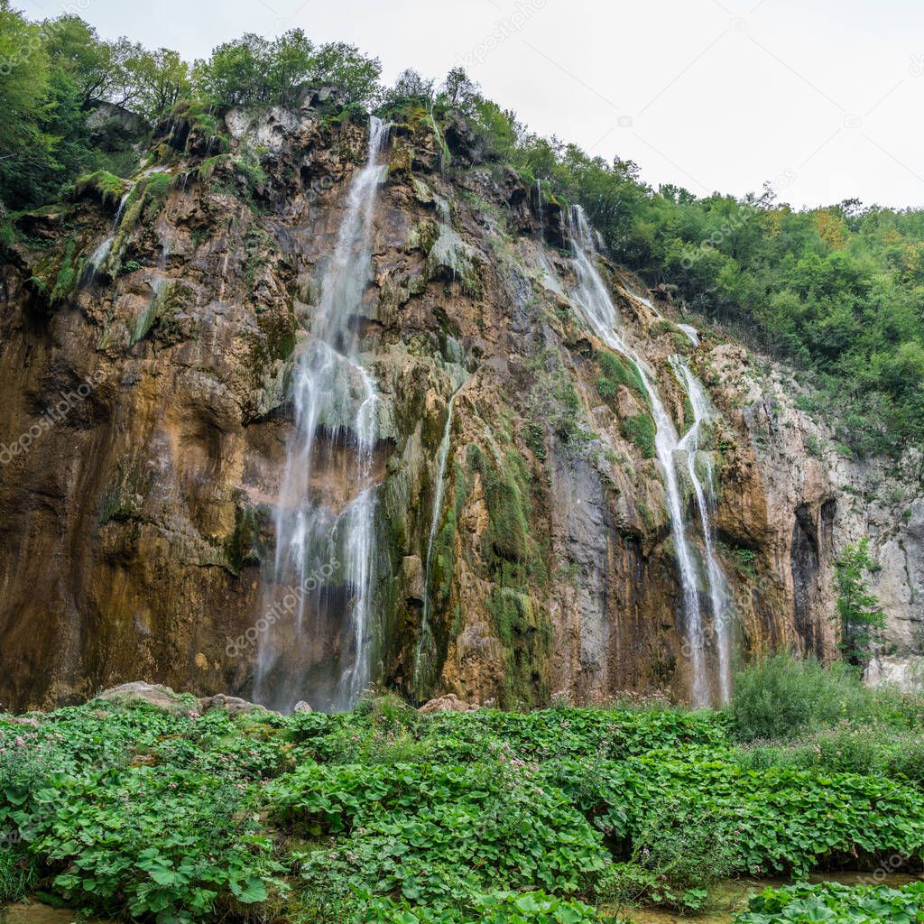 Plitvice Lakes National Park is one of the oldest and largest national parks in Croatia and UNESCO World Heritage.  Waterfall and green rocky hills inside the park. Travelling around Europe.