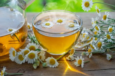 Çaydanlık ve çay bardağının yanında papatya çayı çiçeği. Kırsal ya da kırsal arkaplan.