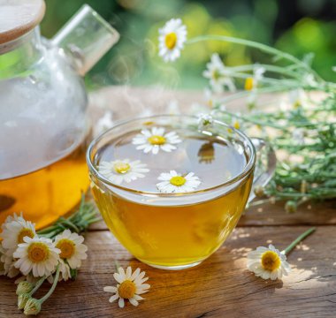 Çaydanlık ve çay bardağının yanında papatya çayı ve papatya çiçeği. Kırsal ya da kırsal arkaplan.