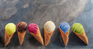 Gri arka planda waffle külahlı çeşitli renkli dondurmalar. Manzarayı aç.