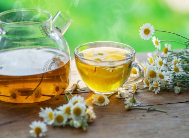 Çaydanlık ve çay bardağının yanında papatya çayı ve papatya çiçeği. Kırsal ya da kırsal arkaplan.