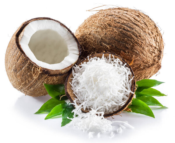 Cracked coconut fruit with white flesh and shredded coconut flakes isolated on white background.