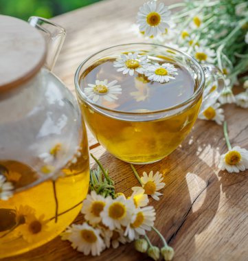 Çaydanlık ve çay bardağının yanında papatya çayı ve papatya çiçeği. Kırsal ya da kırsal arkaplan.