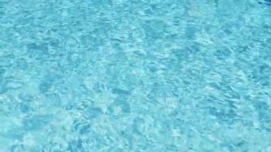 Havuzun suyunda dalgalanmalar. Şeffaf, ışıl ışıl ve hareketli suyun davetkar yüzeyi. Yukarıdan bak. Yavaş çekim ve döngülü video.