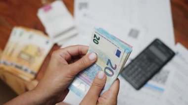 Kadın eli masada otururken avro sayıyor. Faturalar ve makbuzlar masanın üzerinde. Ev bütçesinin hesaplanması ya da küçük bir işletmenin geliri.. 