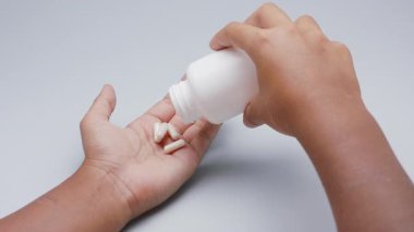 Beyaz kapsüller ya da plastik şişeden açık gri arka plana dökülen haplar. İlaç, sağlık, takviye ve ilaç tedavisi kavramı.