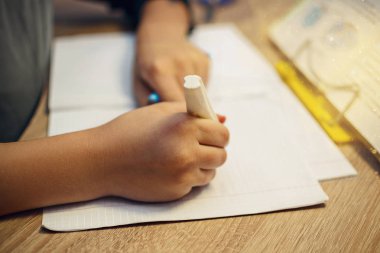 Okul ödevlerini yapıyor masada oturan genç çocuk