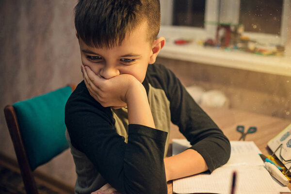 Young boy sitting at the table doing his school homework